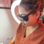 Vanessa Hill in protective eyewear holding the Candela laser handpiece