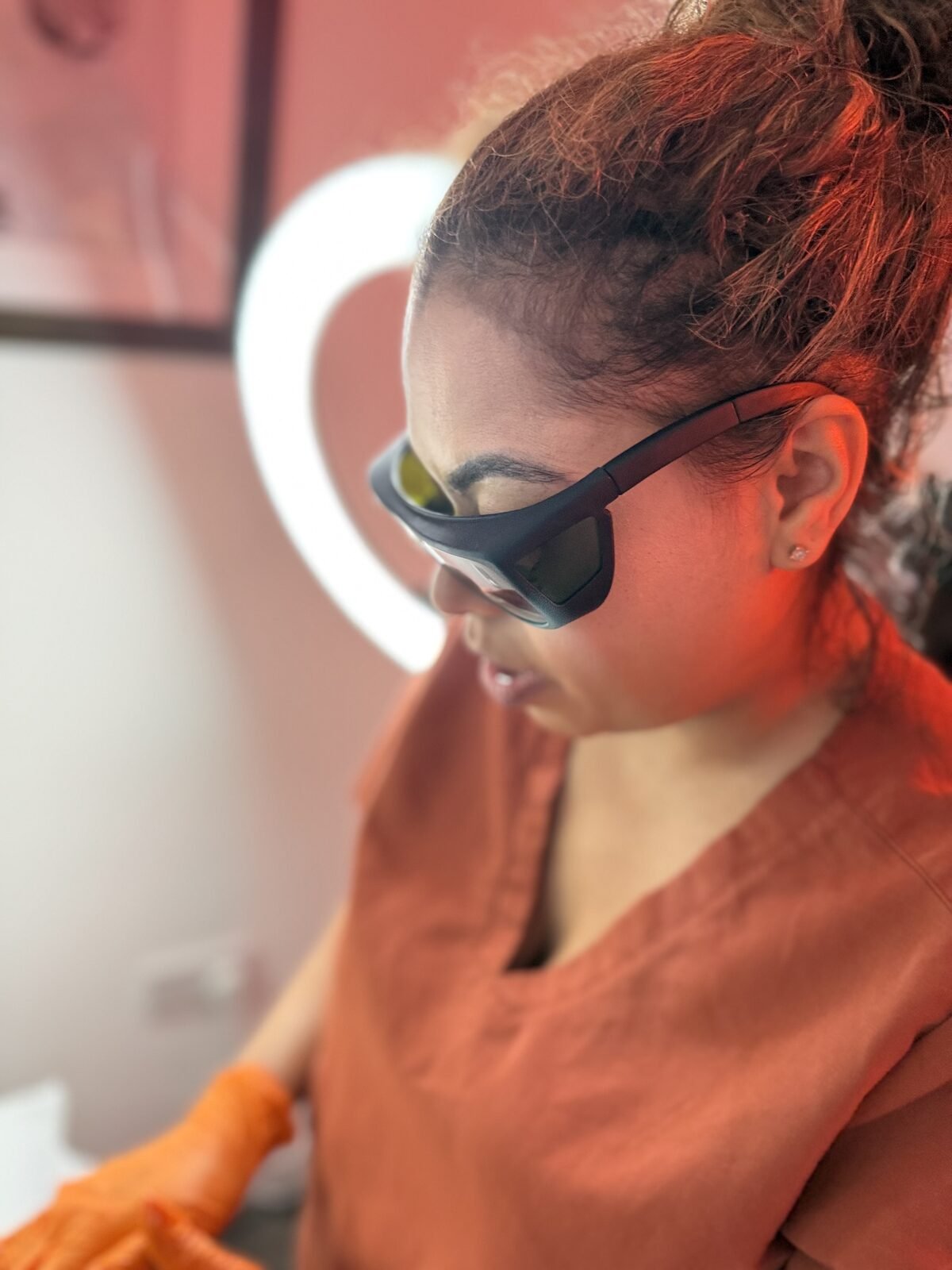 Vanessa Hill in protective eyewear holding the Candela laser handpiece