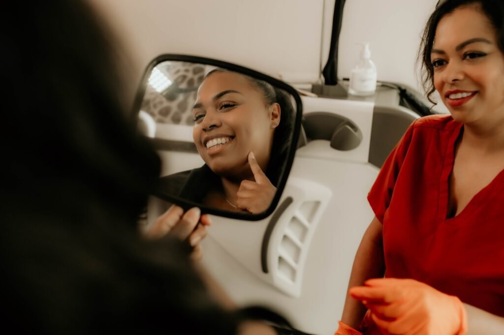 A client smiling into a hand mirror after laser treatment with Vanessa Hill